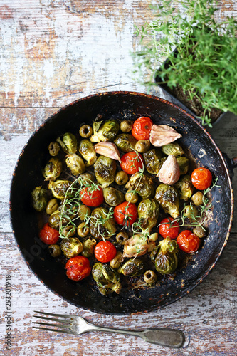 Baked Brussels sprouts in a pan with cherry tomatoes, garlic and olives. Vegan food. Diet concept. Autumn food.