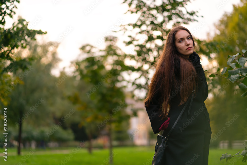 Beautiful girl in the park in a black coat walk in the park. Beautiful girl in the park in a black coat walk in the park.