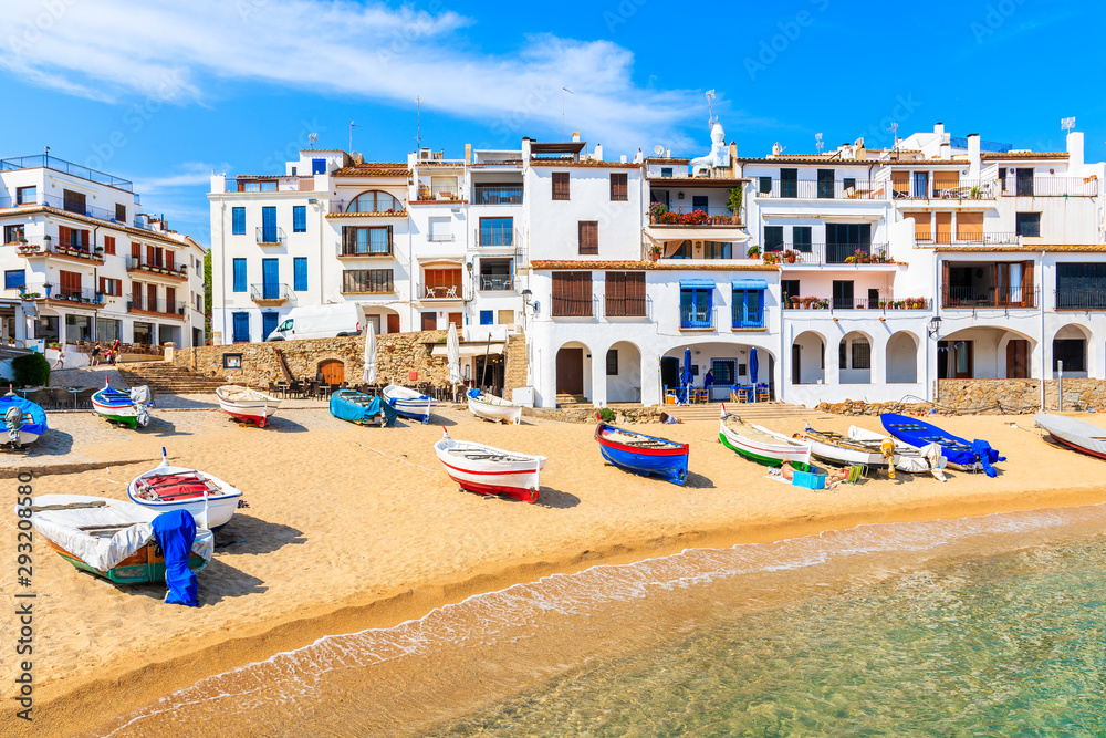 Fishing boats on beach in Port Bo with colorful houses of old town of Calella de Palafrugell in background, Catalonia, Spain