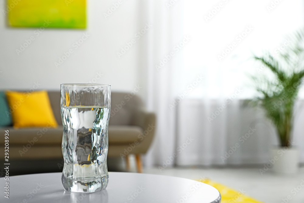 Glass of water on table in room, space for text. Refreshing drink Glass of water on table in room, space for text. Refreshing drink