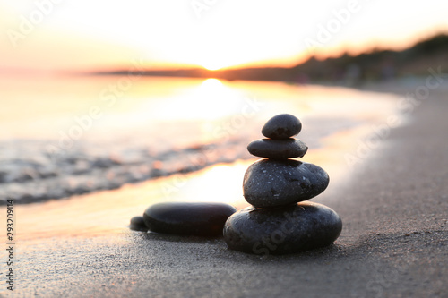 Dark stones on sand near sea at sunset  space for text. Zen concept