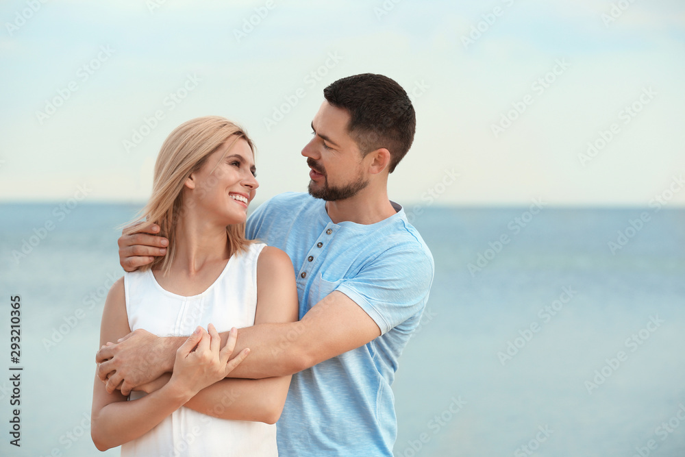 Happy romantic couple spending time together on beach, space for text