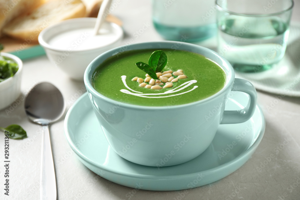 Cup of healthy green soup with fresh spinach on light table Cup of healthy green soup with fresh spinach on light table