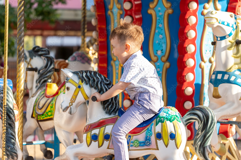 Smiling child riding a toy horse carousel 