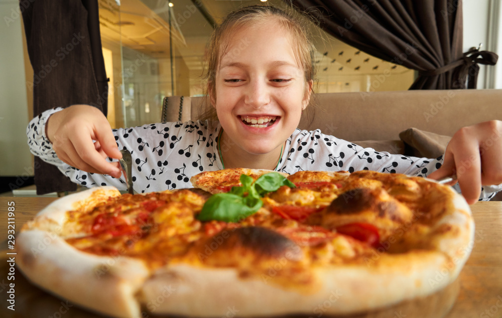 little girl eating pizza and having fun, sitting on sofa in city cafe little girl eating pizza and having fun, sitting on sofa in city cafe