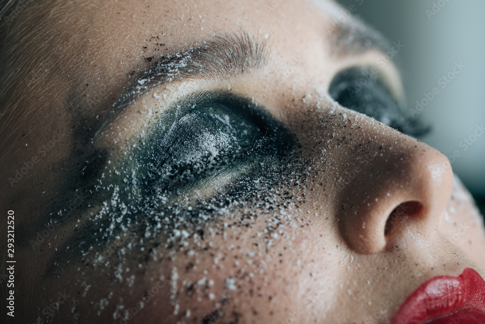 A stunning make-up on the face of a beautiful young girl, beauty makeup, oil on her face and sparkly green with priority red