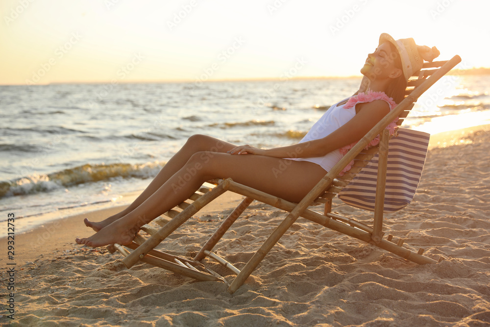 Young woman relaxing in deck chair on beach Young woman relaxing in deck chair on beach