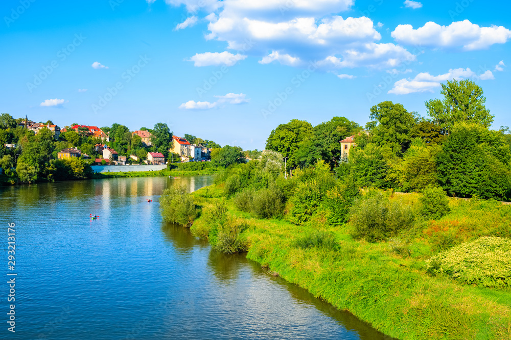 View of Vistula river with houses in background on sunny summer day, Krakow, Poland