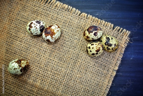Quail eggs on sackcloth and a black wooden background.