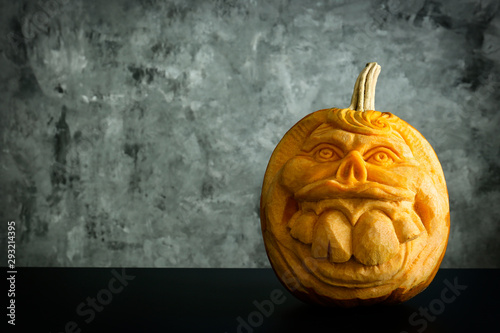 Orange pumpkin carved into creepy and funny Jack o Lantern w/ glowing eyes on dark background. All hallows night. Copy space, close up, top view. Halloween party decoration. Trick or treat concept. photo