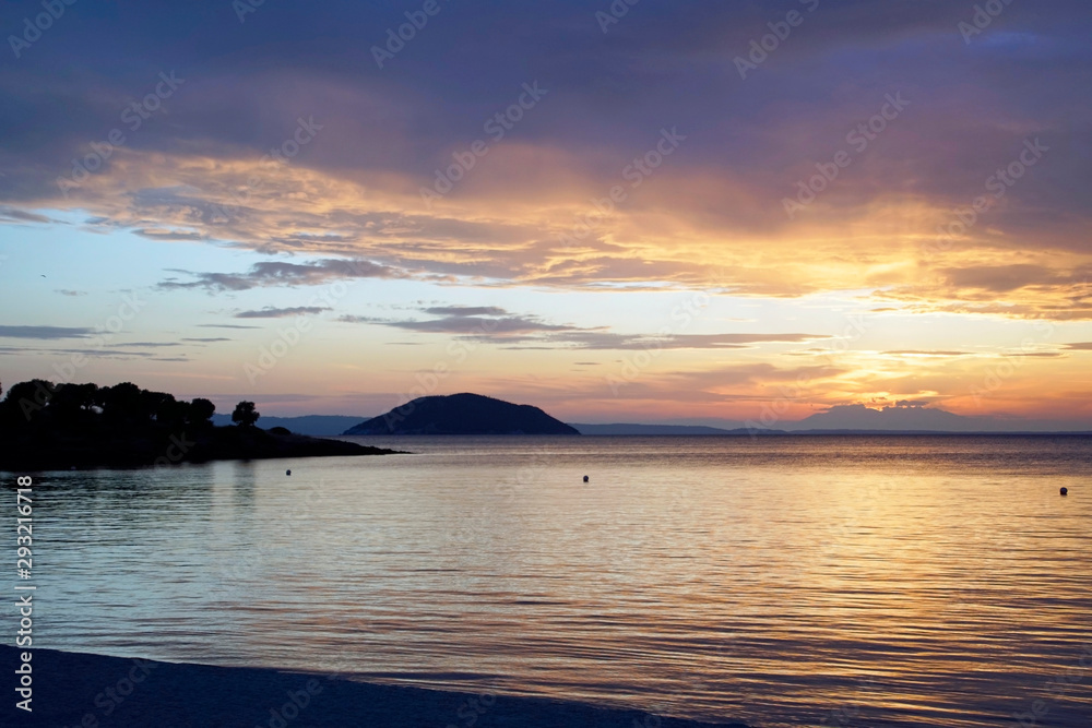 Horizontal shot. Empty beach in the evening at sunset. . Silhouettes and coastline. Sea bright sky. Greece Sithonia. Horizon. Clouds and rays of the sun. Bird island Horizontal shot. Empty beach in the evening at sunset. . Silhouettes and coastline. Sea bright sky. Greece Sithonia. Horizon. Clouds and rays of the sun. Bird island
