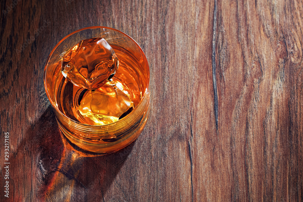 Glass of whiskey with ice on wooden bar table - obrazy, fototapety, plakaty 