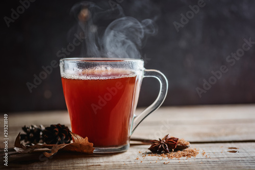 Hot tea with spices with steam on a wooden background, rustic style, autumn postcard, copy space