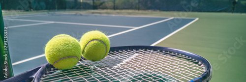 Tennis court panorama background with blue racket and two tennis balls ready to play match on outdoor courts summer sport lifestyle. Mobile photo picture.
