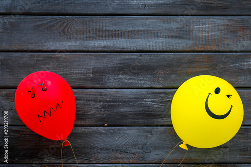 Treat depression concept. Balloons with frustrated and smiling faces on dark wooden background top view space for text