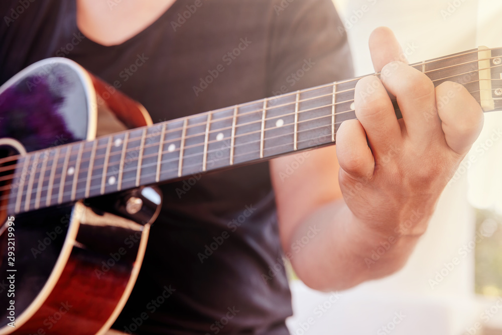 Hands of a young male playing acoustic guitar in the garden Hands of a young male playing acoustic guitar in the garden