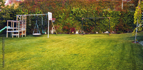Fototapeta Naklejka Na Ścianę i Meble -  Backyard garden of a house with children playhouse, basketball hoop and soccer goal post