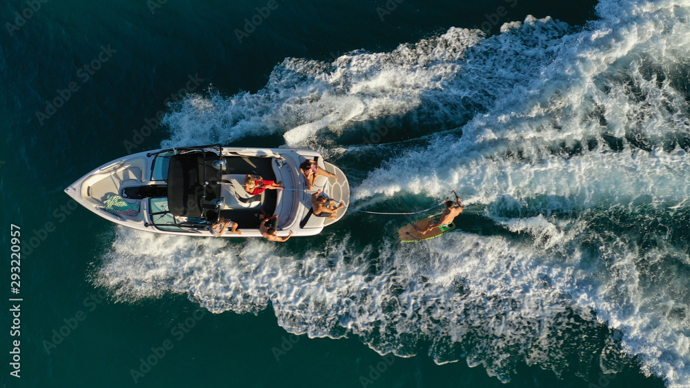 Aerial photo of woman practising waterski in Mediterranean bay with emerald sea at sunset