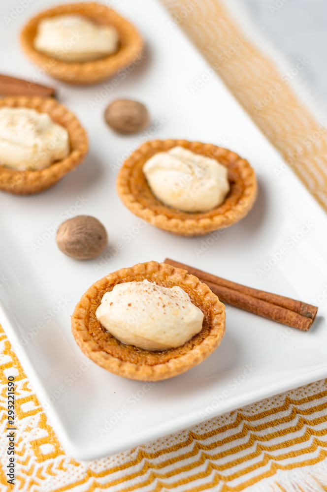 Sweet butter tartlet close-up. Mini sugar pies (or butter tarts) with a crisp pastry crust, a sweet filling and pumpkin spice whipped cream on top. A tasty dessert for fall holidays like halloween!