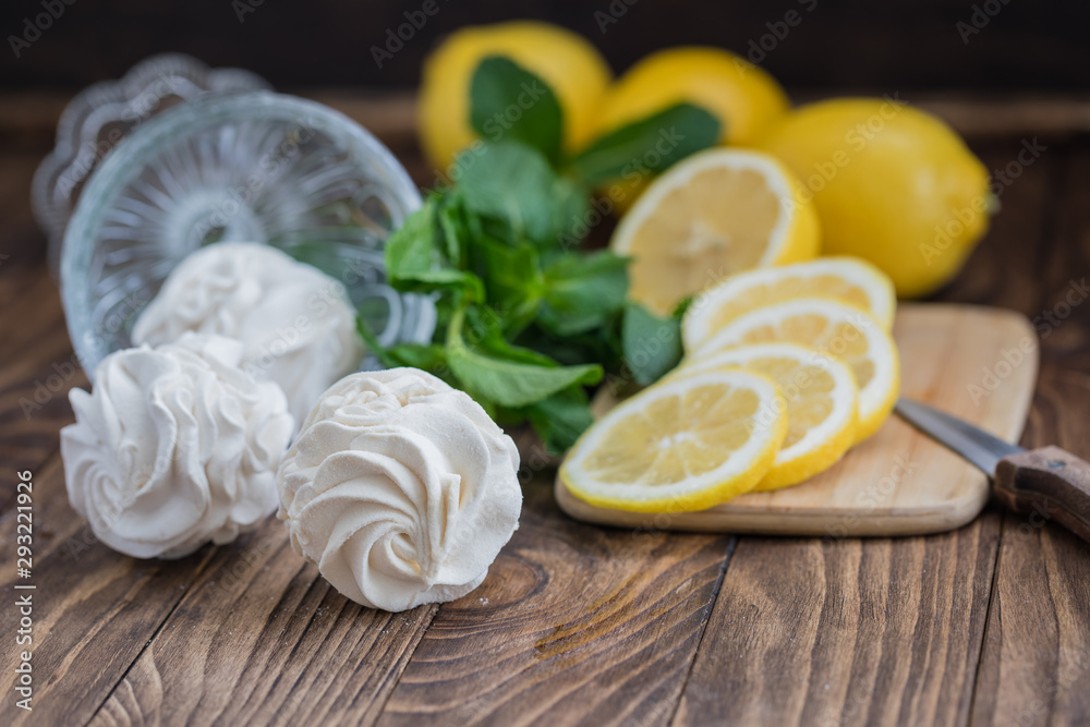 Yellow and white russian marshmallows zephyr on wooden table with lemon slices and mint leaves to show the flavour Yellow and white russian marshmallows zephyr on wooden table with lemon slices and mint leaves to show the flavour
