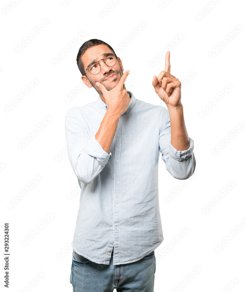 Hesitant young man pointing up with his finger Hesitant young man pointing up with his finger