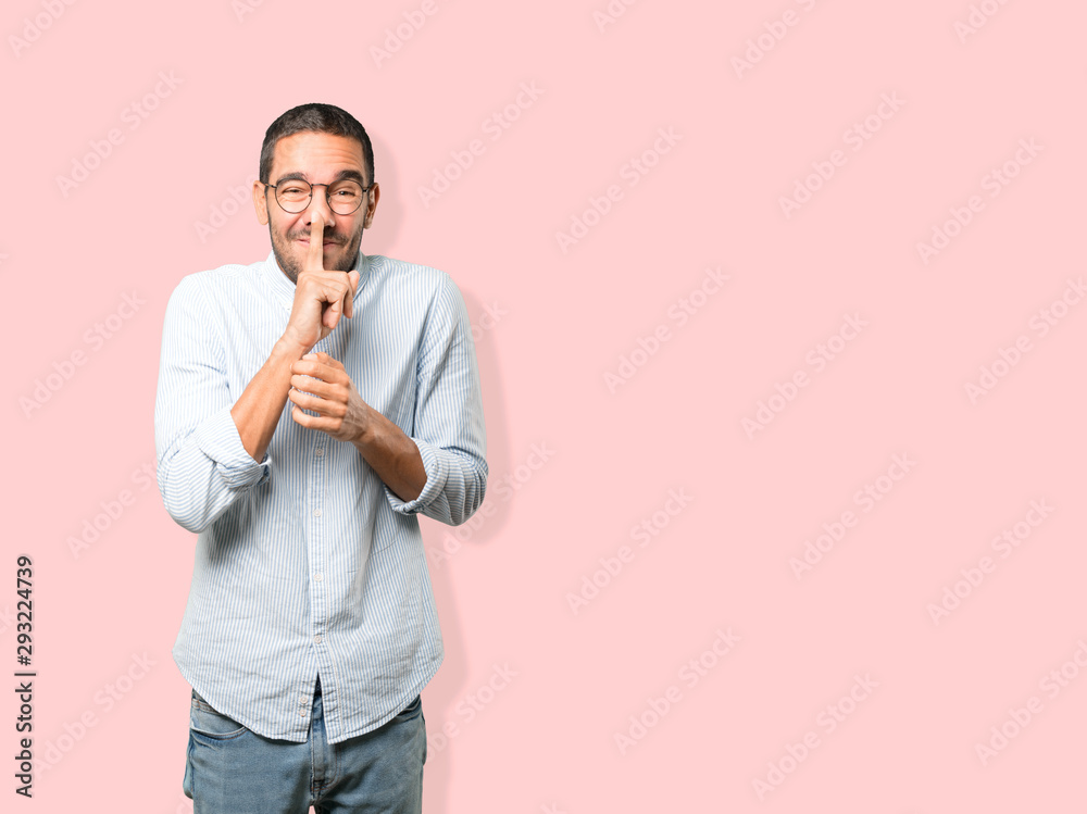 Amazed young man asking for silence gesturing with his finger Amazed young man asking for silence gesturing with his finger