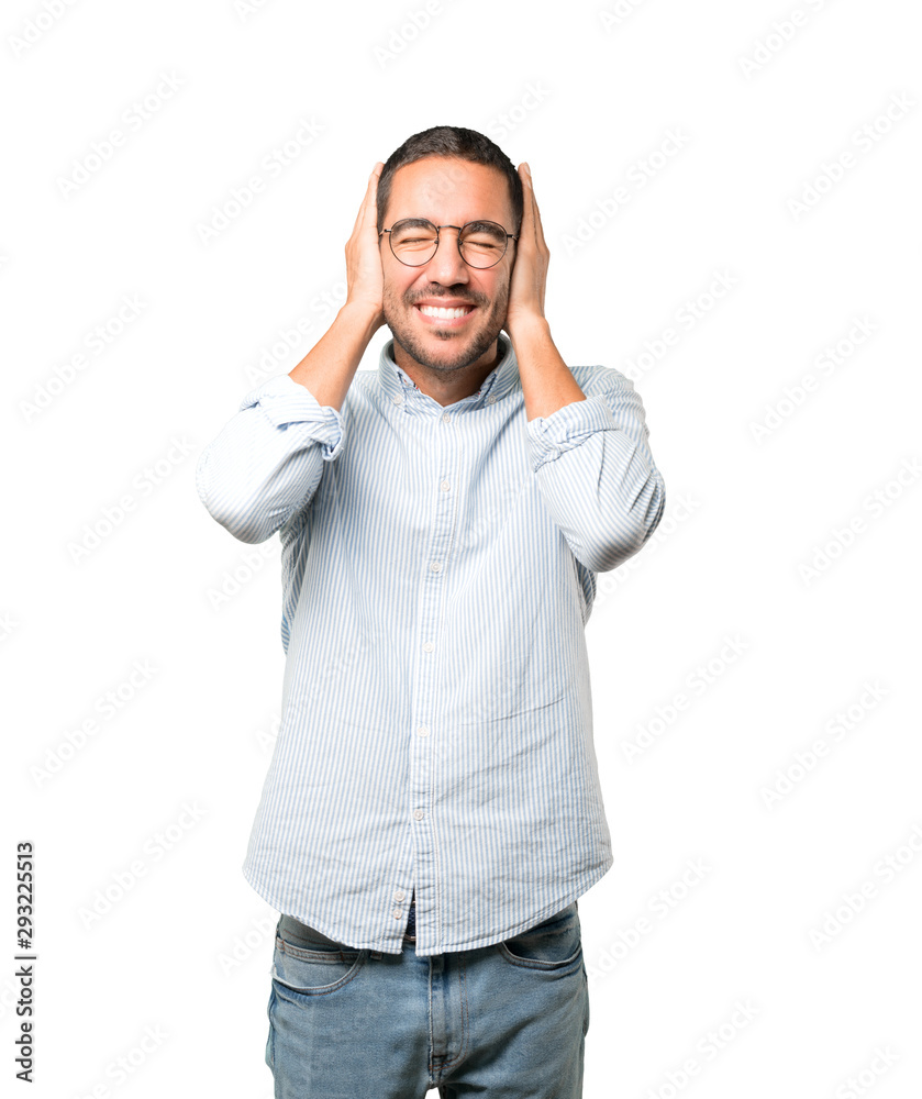 Young man worried about loud noises and covering his ears Young man worried about loud noises and covering his ears