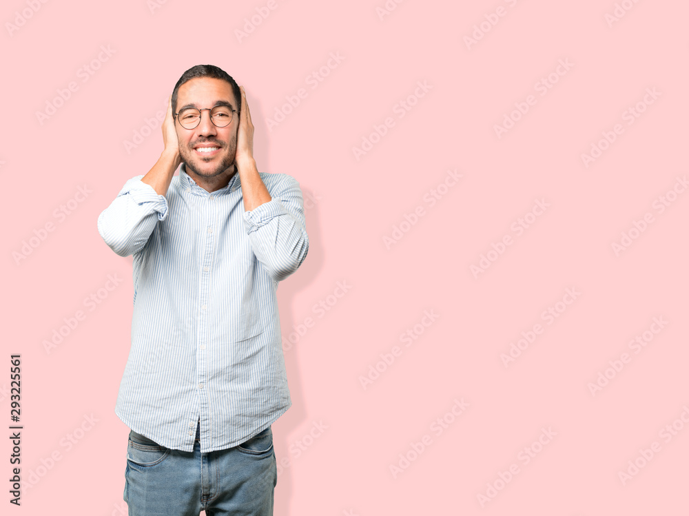 Young man worried about loud noises and covering his ears Young man worried about loud noises and covering his ears