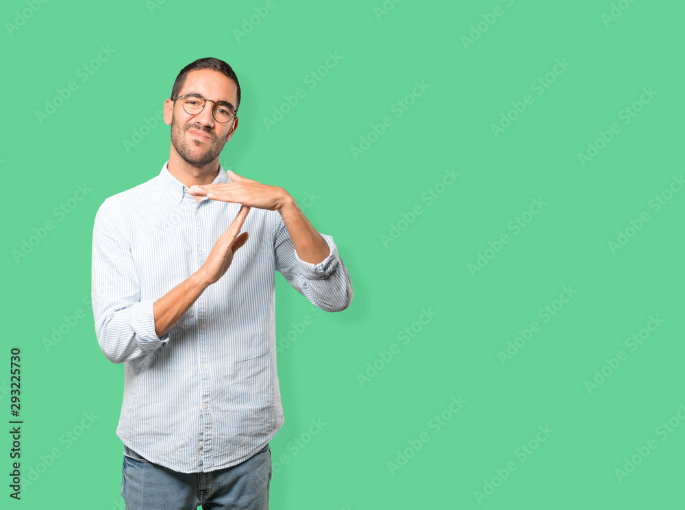 Stressed young man making a time out gesture with his hands Stressed young man making a time out gesture with his hands