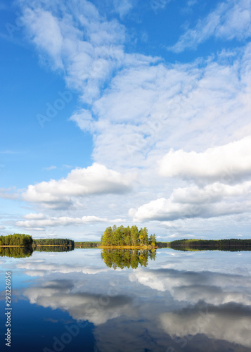 Fototapeta Naklejka Na Ścianę i Meble -   Landscape with the island on the lake and blue sky. Forest and beautiful blue sky with white clouds and reflection on the lake water.
