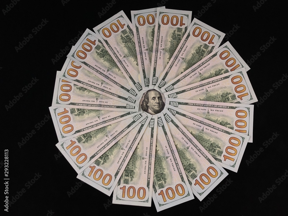 Banknotes of 100 US dollars lie in a circle. The image of Benjamin Franklin is surrounded by hundred-dollar bills. American money on the table. Concept: currency, dollar exchange rate