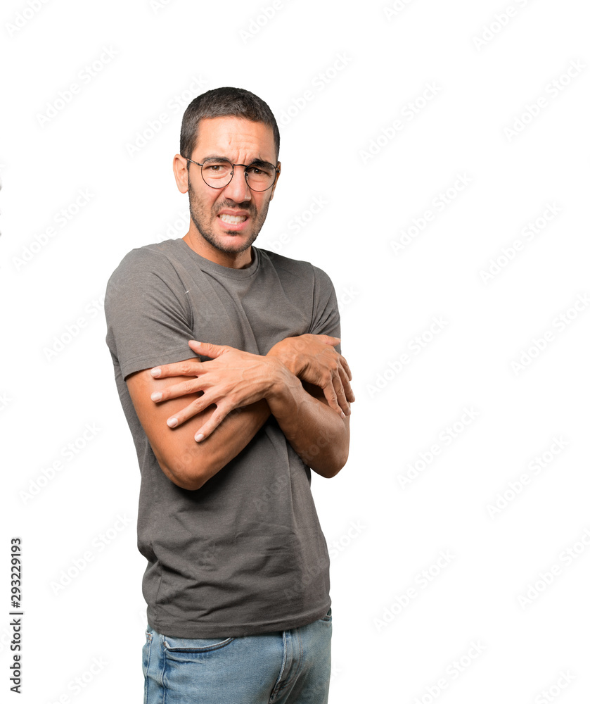 Concerned young man making a gesture of being cold Concerned young man making a gesture of being cold