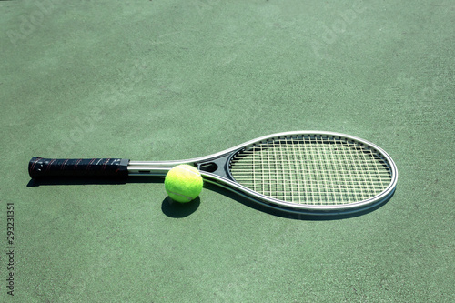 single big tennis racket on a green court with a tennis ball © Nataliia
