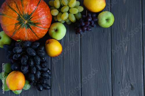 Autumn harvest of vegetables and fruits on a dark wooden background with a place for inscription. Pumpkin, peach, apples, grapes. Vitamins for Healthy Nutrition in Autumn photo