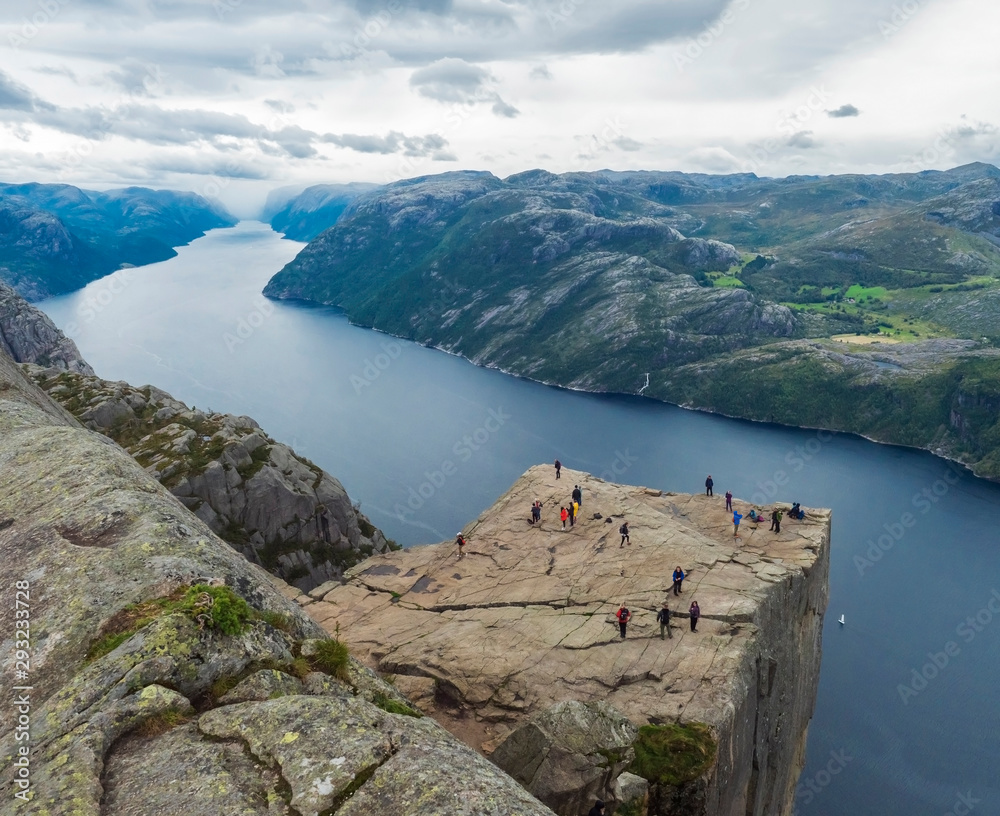 Preikestolen massive cliff at fjord Lysefjord, famous Norway viewpoint with group of tourists and hikers.Moody autumn day. Nature and travel background, vacation and hiking holiday concept.