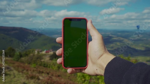 Young man hand hold phone with vertical green screen background mountains at sunny day forest field communication connection digital gadget greenery internet lifestyle mobile online slow motion photo