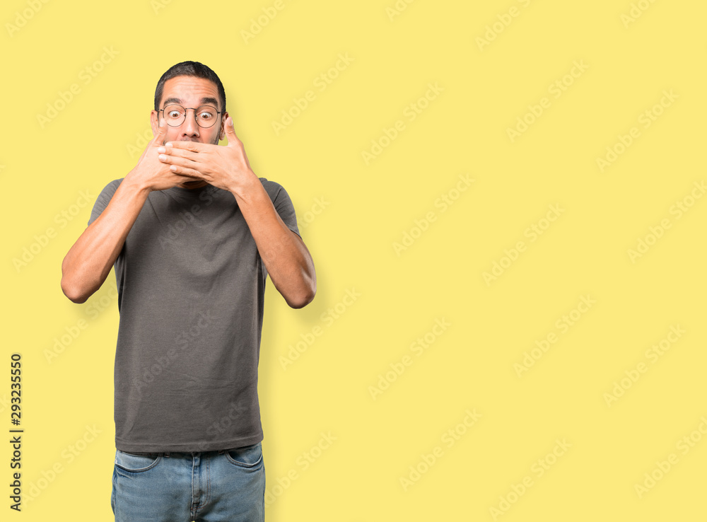 Young man covering his mouth with his hands Young man covering his mouth with his hands