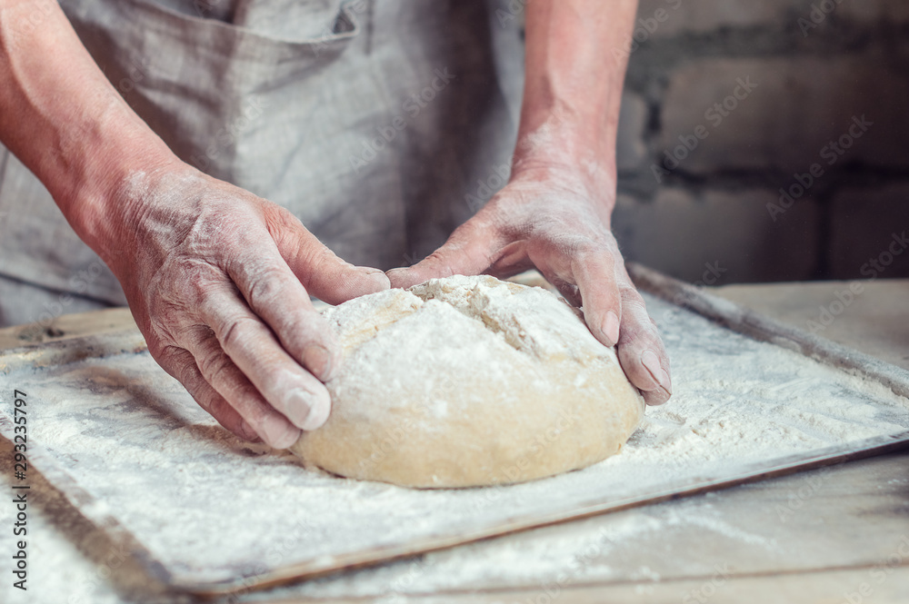 Wheat bread to the oven. The Baker's hands. Process the dough for wheat bread. Rustic style. Selective focus
