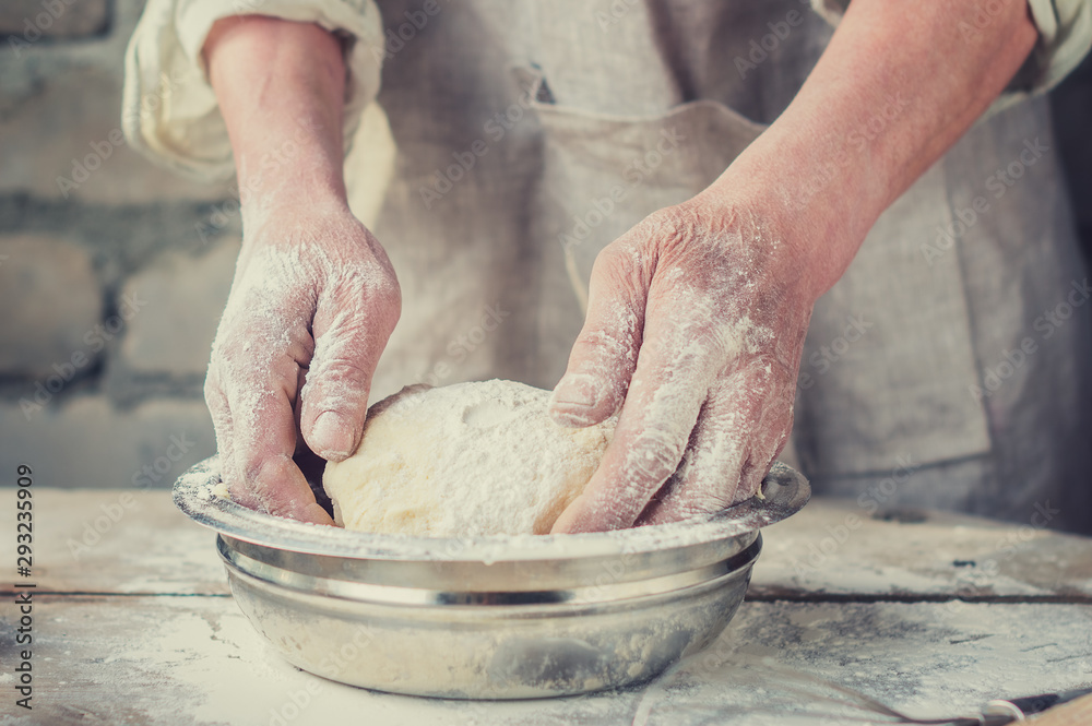 The Baker's hands under dough for wheat bread