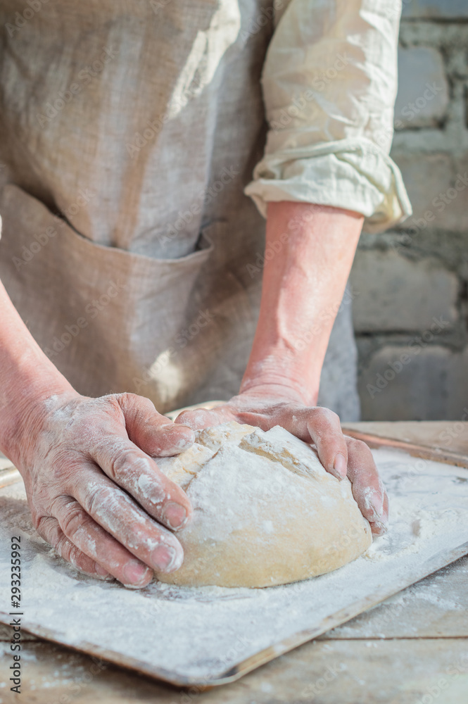 The Baker's hands on a raw wheat bread to the oven. Process the dough for wheat bread.