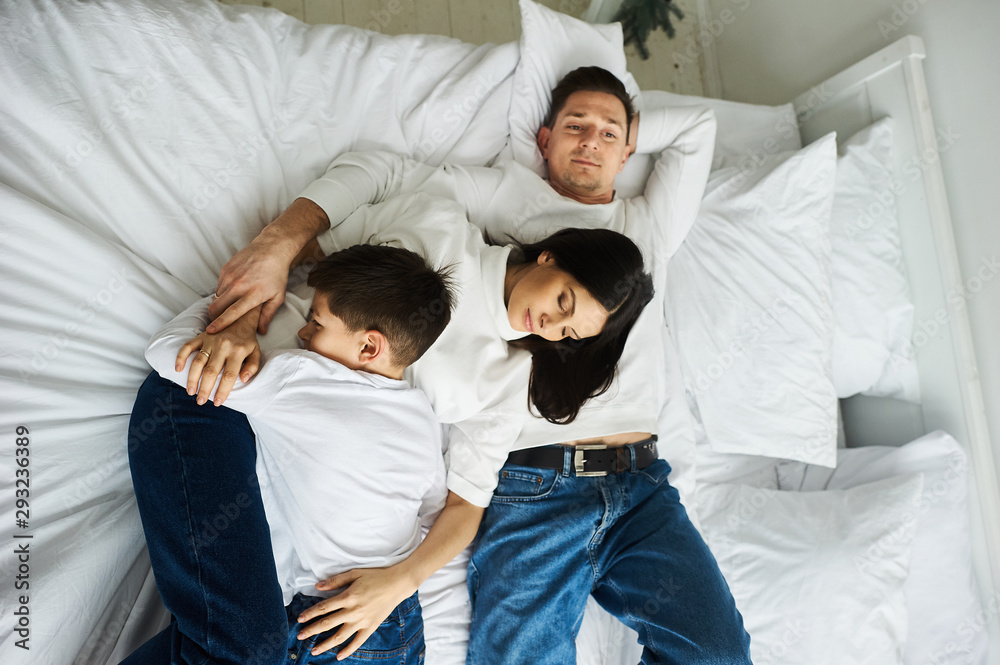 Obraz premium A beautiful young family in the morning bedroomis relaxing and have a fun on a white background