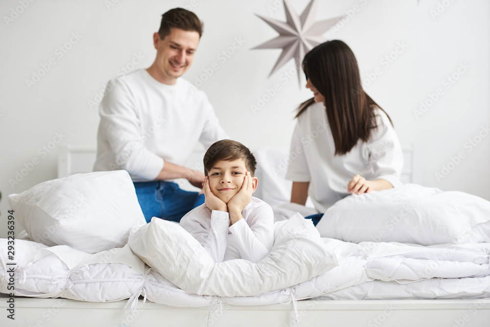 A beautiful young family in the morning bedroomis relaxing and have a fun on a white background A beautiful young family in the morning bedroomis relaxing and have a fun on a white background