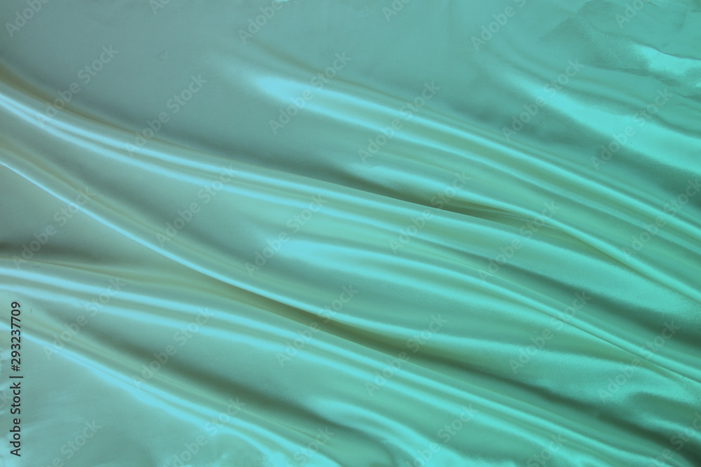 Obraz premium soft folds on delicate green shiny silk, luxury concept, background for the designer, horizontal, close-up, copy space