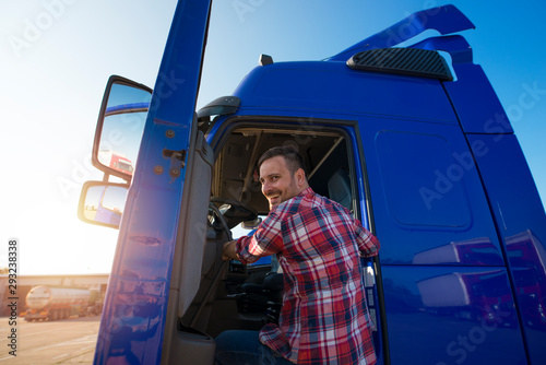 Shot of motivated smiling middle aged truck driver entering his semi truck long vehicle. Happy trucker. Transportation service.