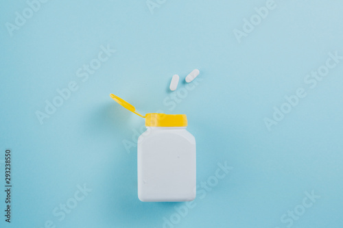 Pills scattered out the bottle on the blue background