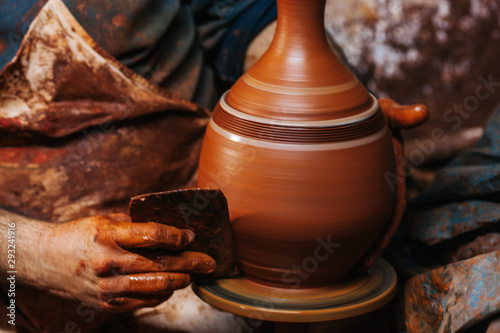 Hands of making clay pot on the pottery wheel ,select focus, close-up. photo