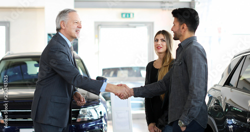 Car dealer giving a handshake to a young couple