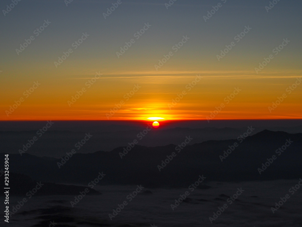 Sunrise at the peak mountains of Chiang Dao, as the sunrise the mountain and mist is dark, in the sky are golden, red, orange, and yellow.