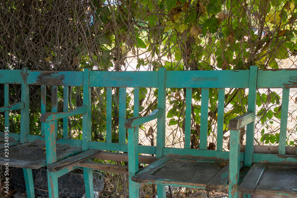 A vintage blue bench from an old movie theater stands under a tree.