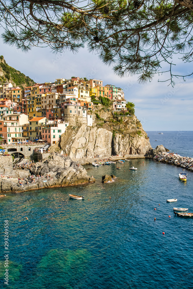 Beautiful view of colorful residential buildings and a bay with boats in the village of Manarola, Italy, National Park of the Cinque Terre